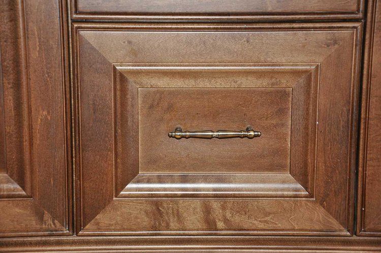 A close up of a wooden cabinet with a brass handle.