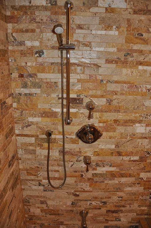 A shower with a brick wall and a shower head.