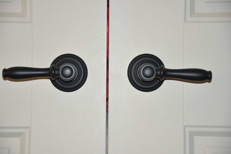A pair of black door handles on a white door