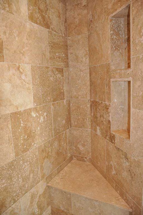 A shower stall with a corner bench and two shelves.
