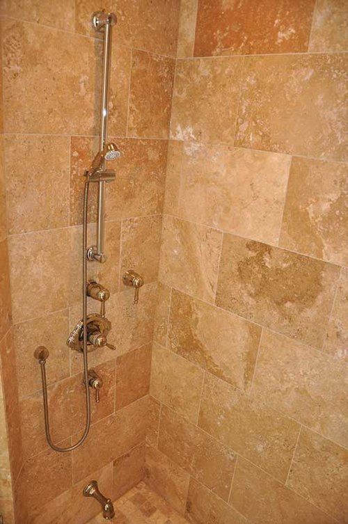 A shower with a tiled wall and a shower head.