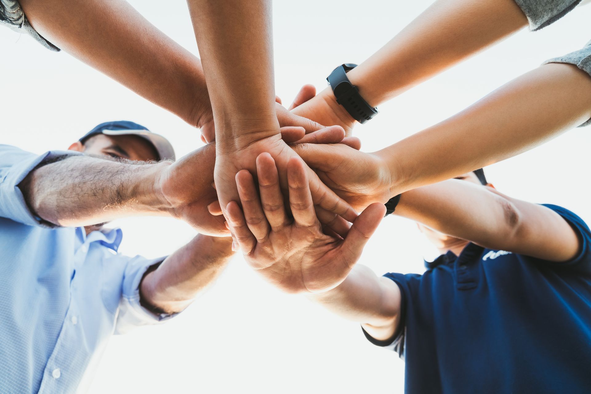 Hands stacked together in a team huddle, demonstrating unity and cummunity support.