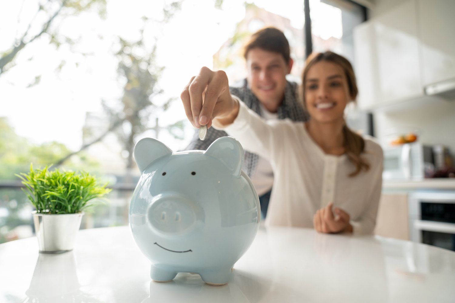 A man and a woman are putting a coin into a piggy bank.