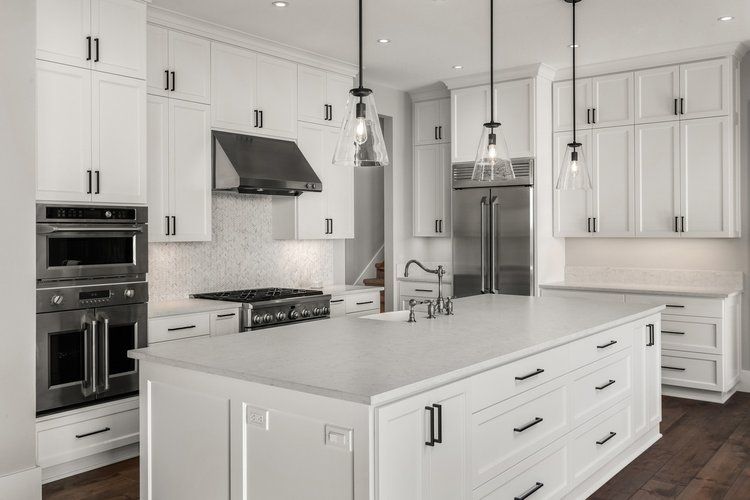 A kitchen with white cabinets , stainless steel appliances , and a large island.