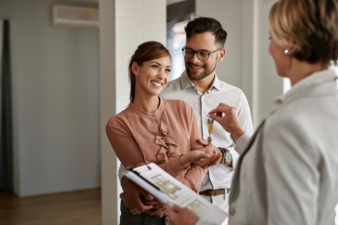 Couple receiving keys from realtor in a new home; they are smiling and happy.