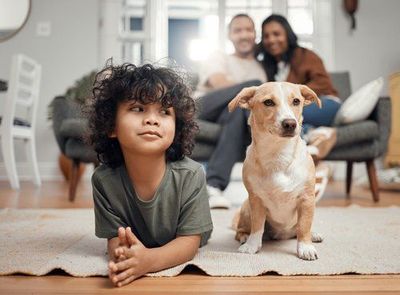 A boy and a dog are laying on the floor in a living room.