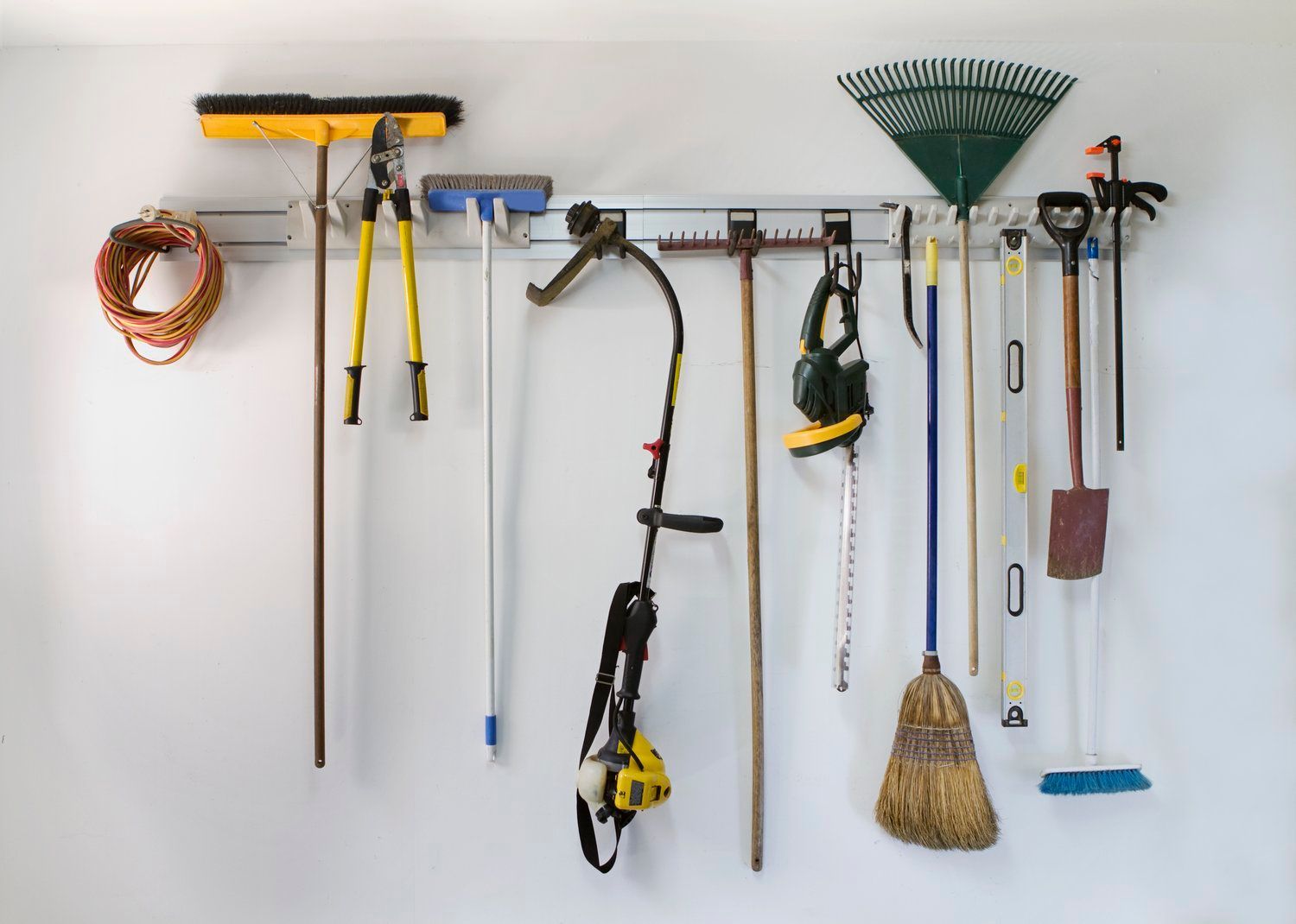 A bunch of gardening tools are hanging on a wall