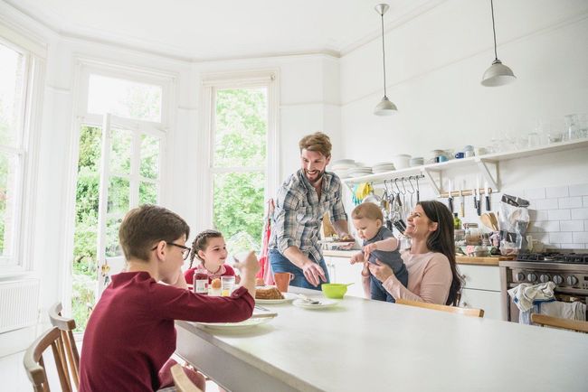 A family is sitting at a table in a kitchen eating food.