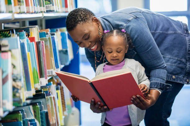 A man and a little girl are reading a book together in a library.