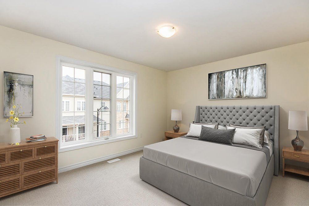 A bedroom with a bed , dresser , nightstand , and two windows.