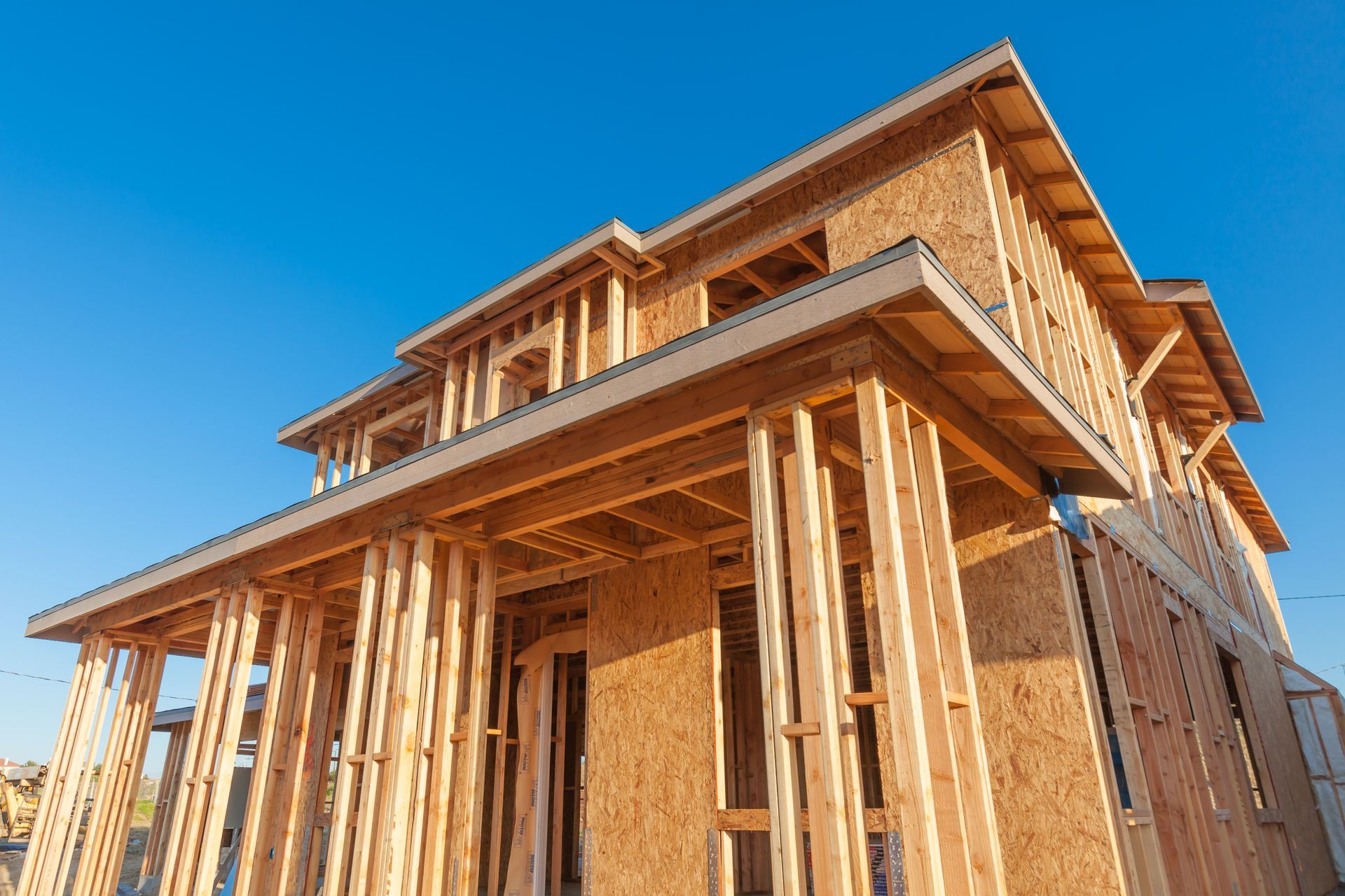 A large wooden house is being built on a sunny day.