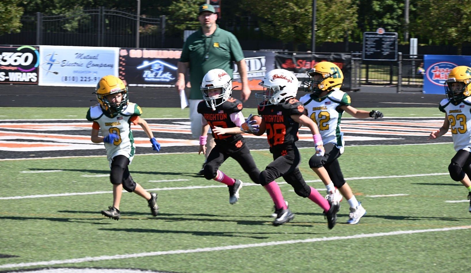 Children in helmets sprint across a football field during a youth game