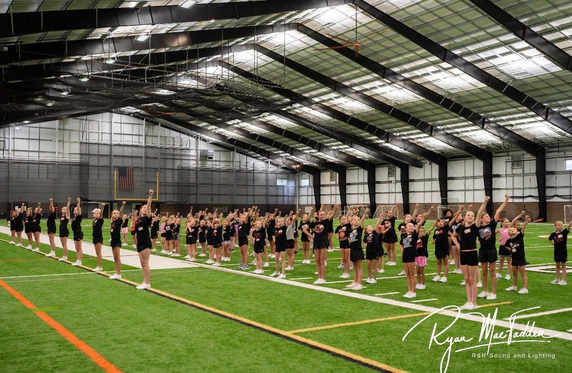 Rows of athletes standing in formation inside an indoor sports facility on green turf