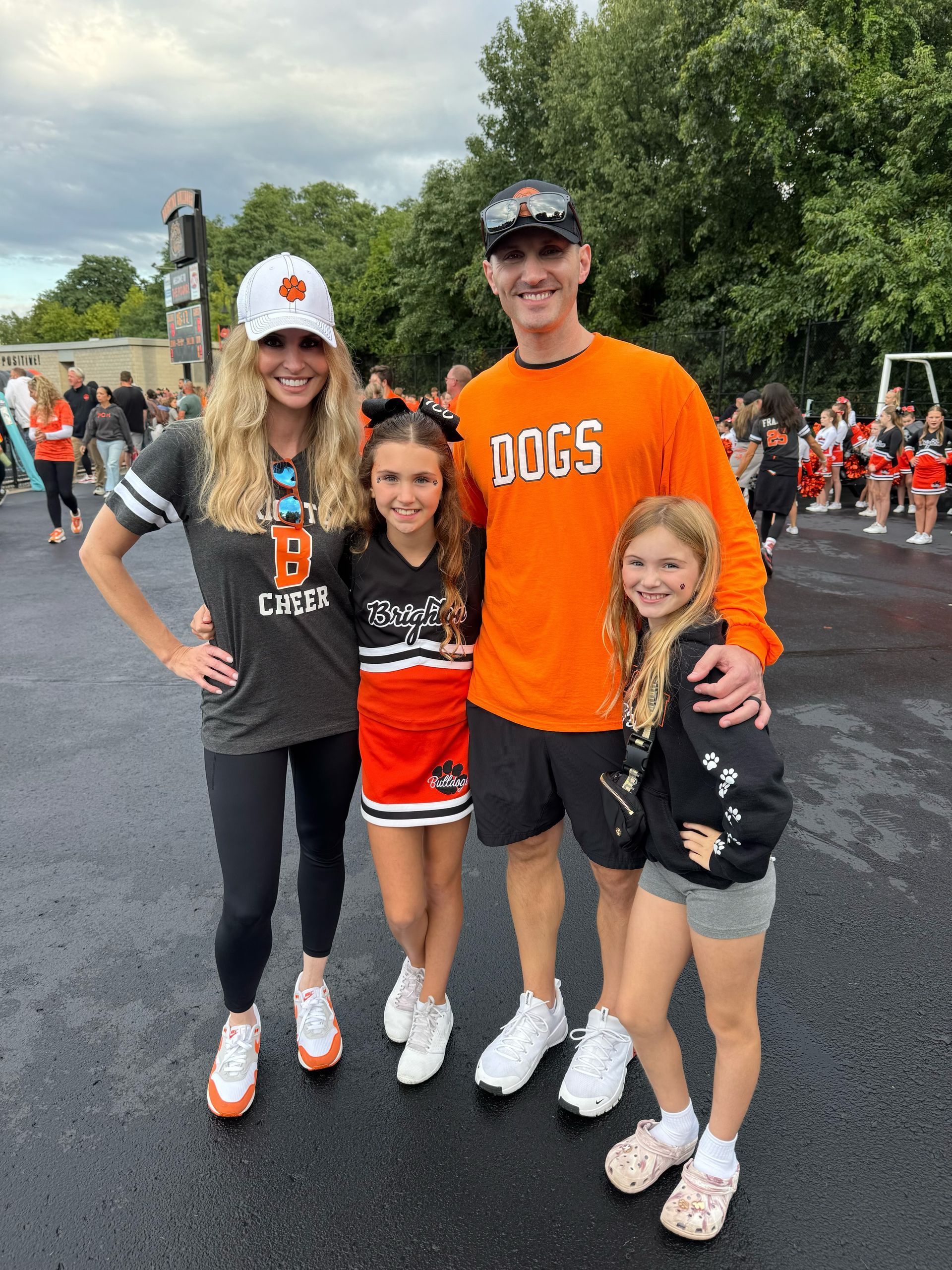 Four people in black and orange baseball outfits posing together at a sports event
