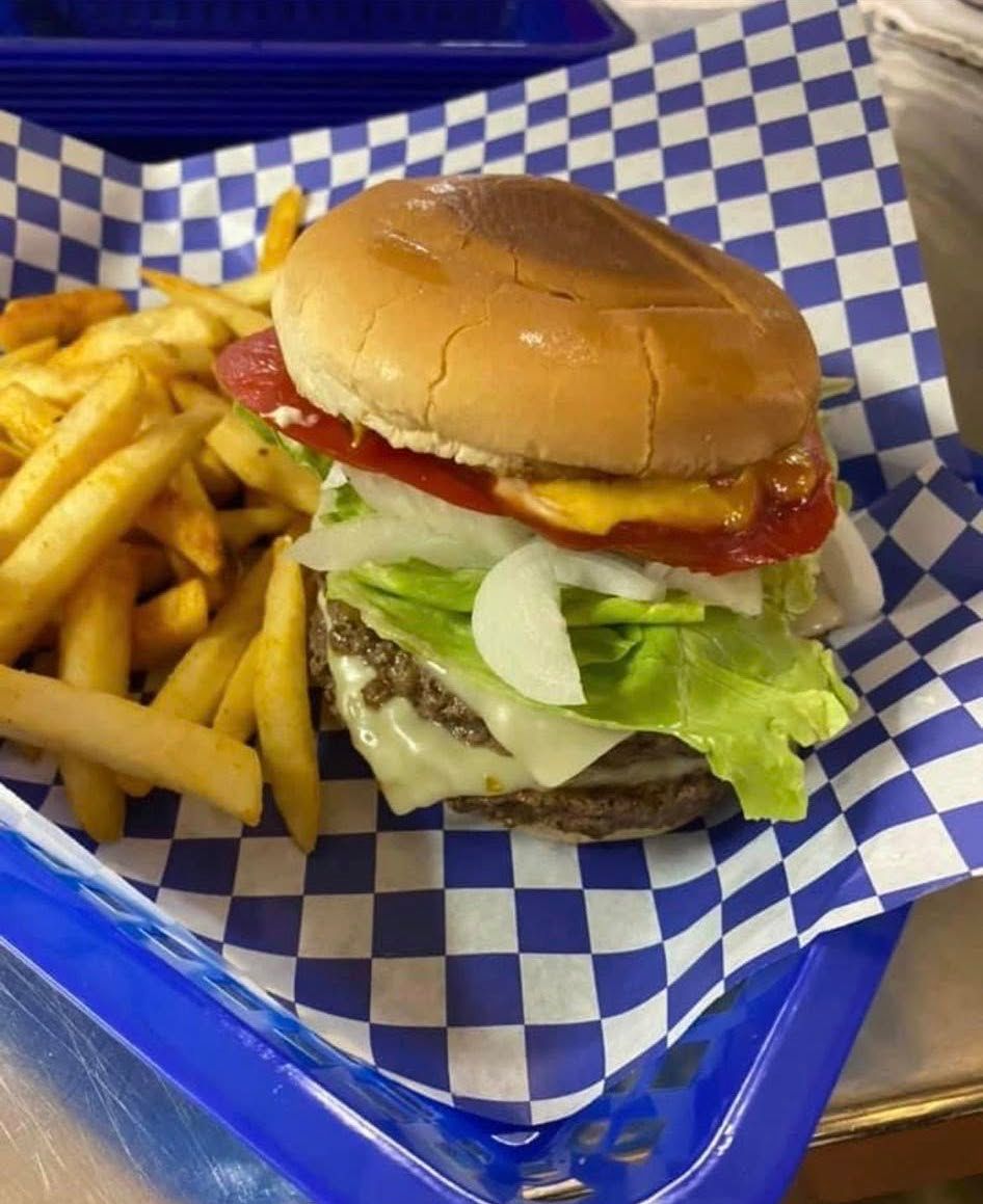 Cheeseburger and fries in a blue basket lined with blue-and-white checkered paper