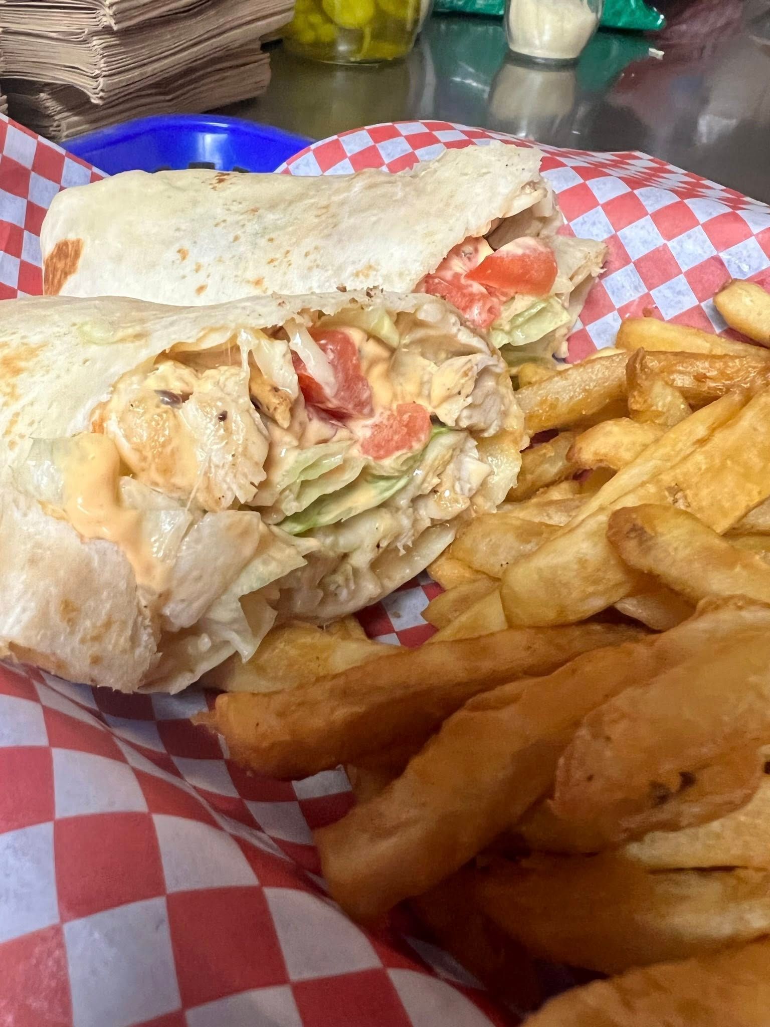 Chicken wrap and fries on a red checkered tray liner.