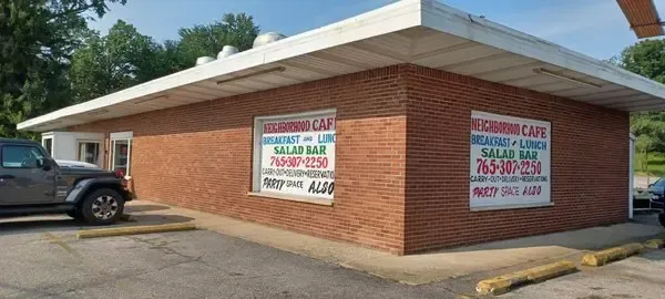 Brick commercial building with large colorful signs and a parked pickup truck on the left.