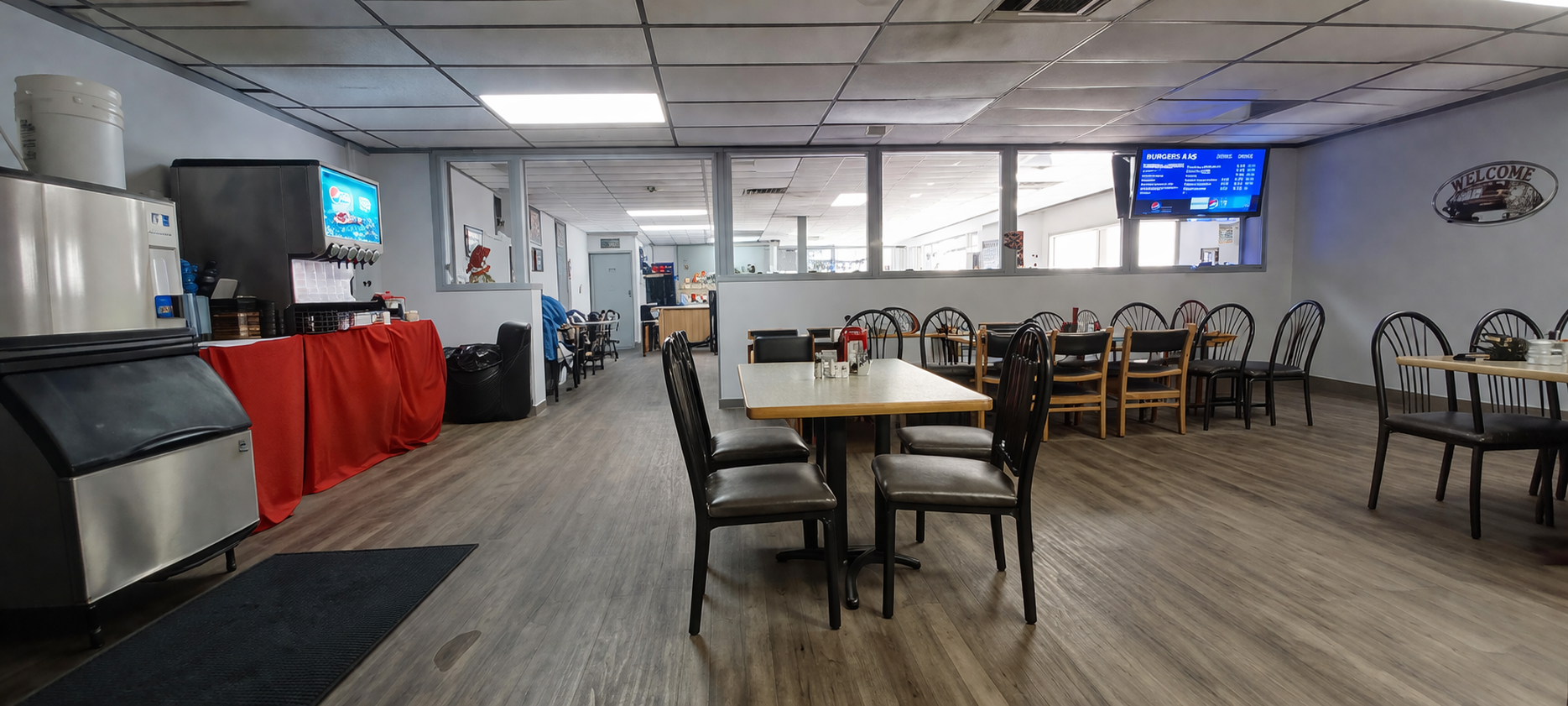 Dining area with tables and chairs, red buffet table, and TVs in a bright room