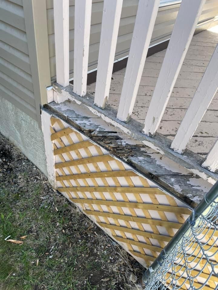 A broken deck railing is sitting next to a chain link fence.