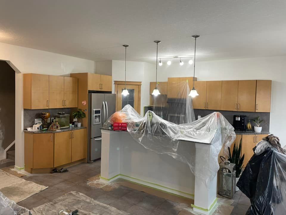A kitchen is being painted and covered in plastic.