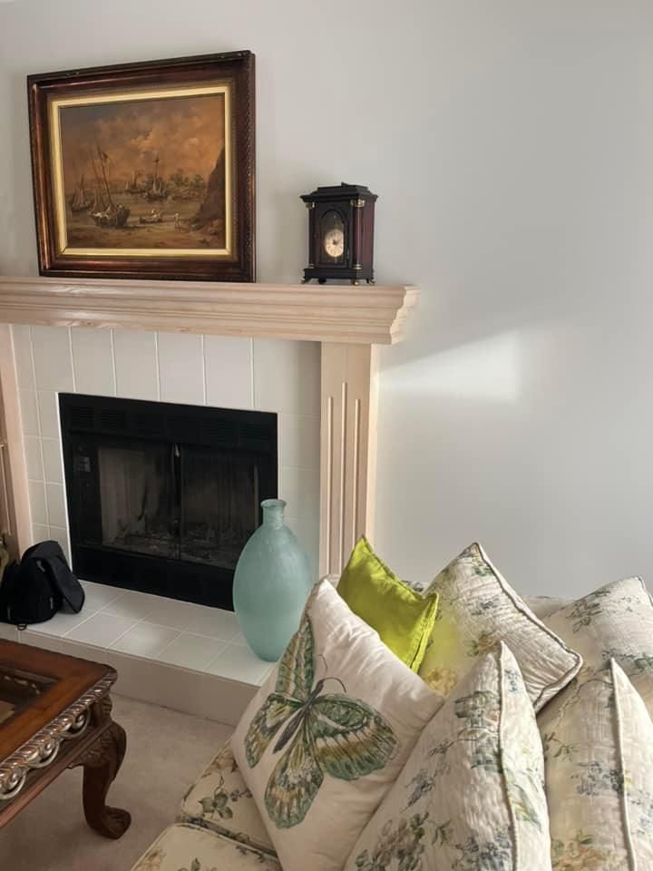 A living room with a fireplace and a clock on the mantle.