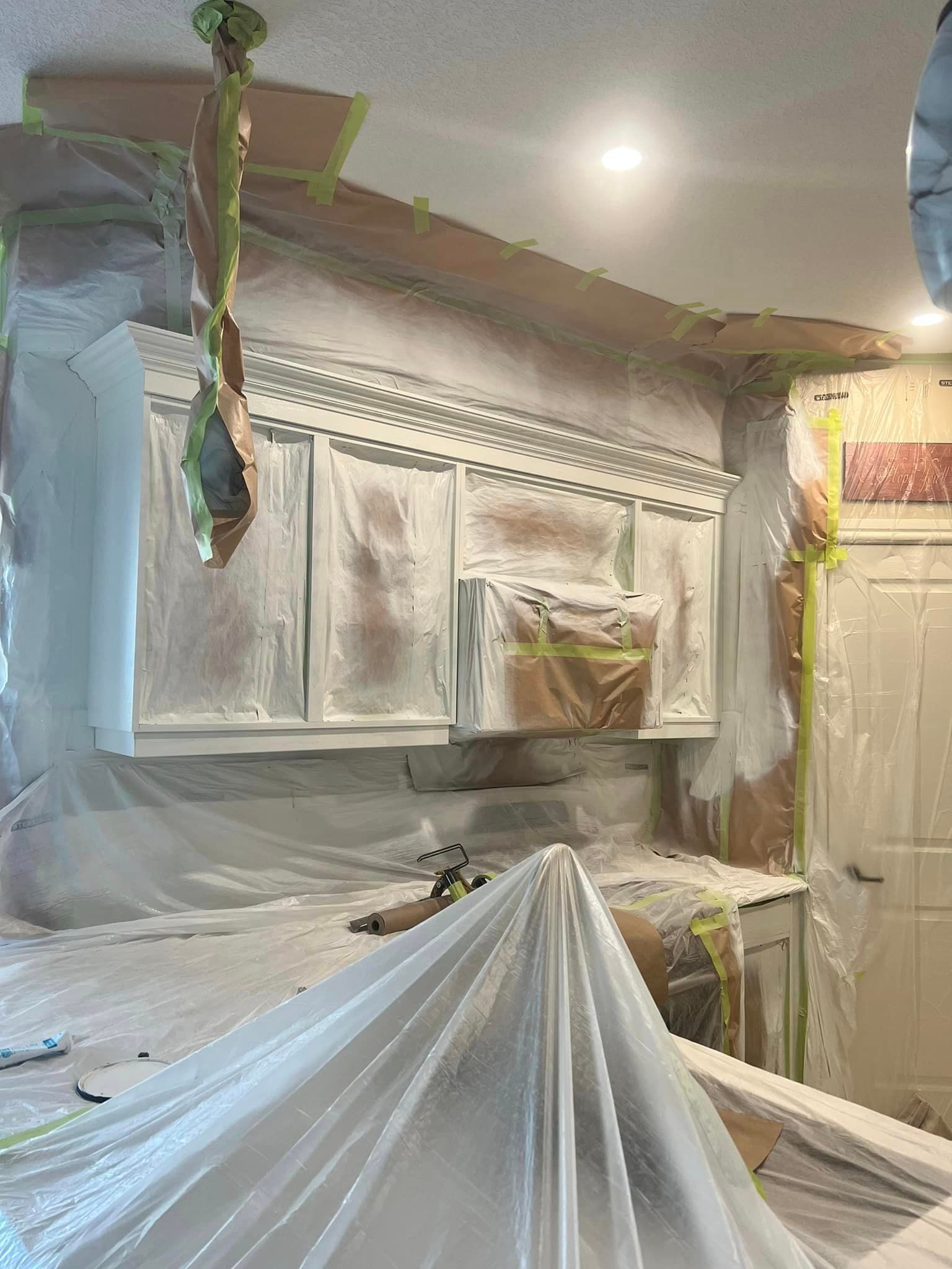 A kitchen is being painted and covered in plastic.