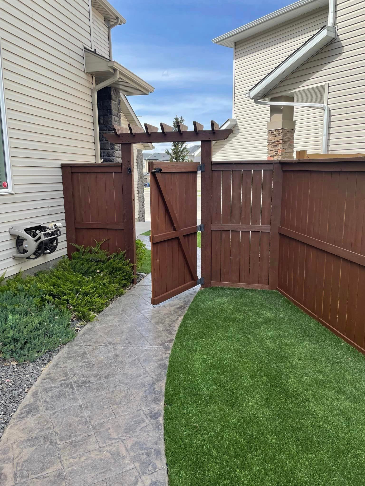 A wooden fence is surrounding a lush green yard.