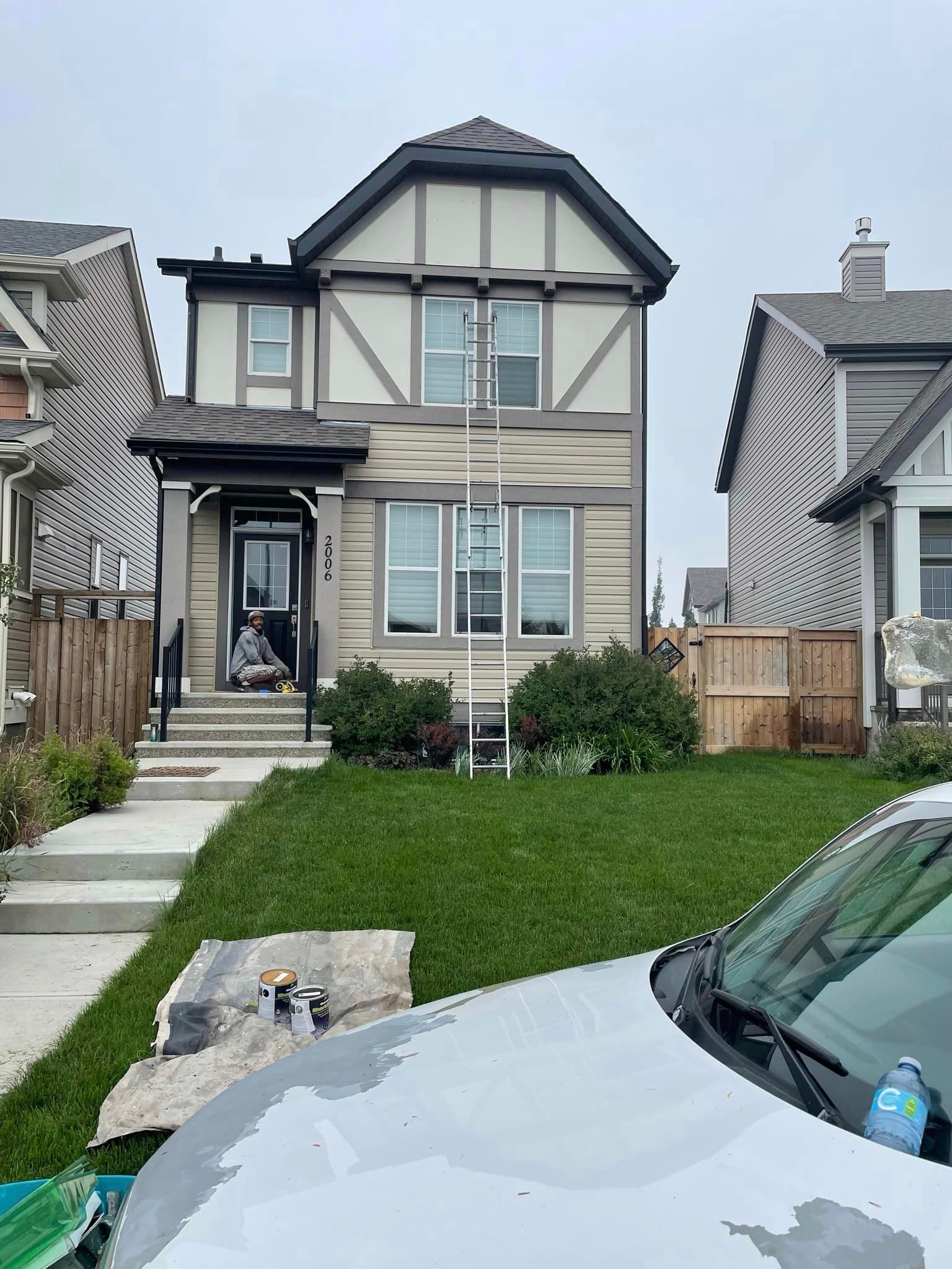 A car is parked in front of a house that is being painted.
