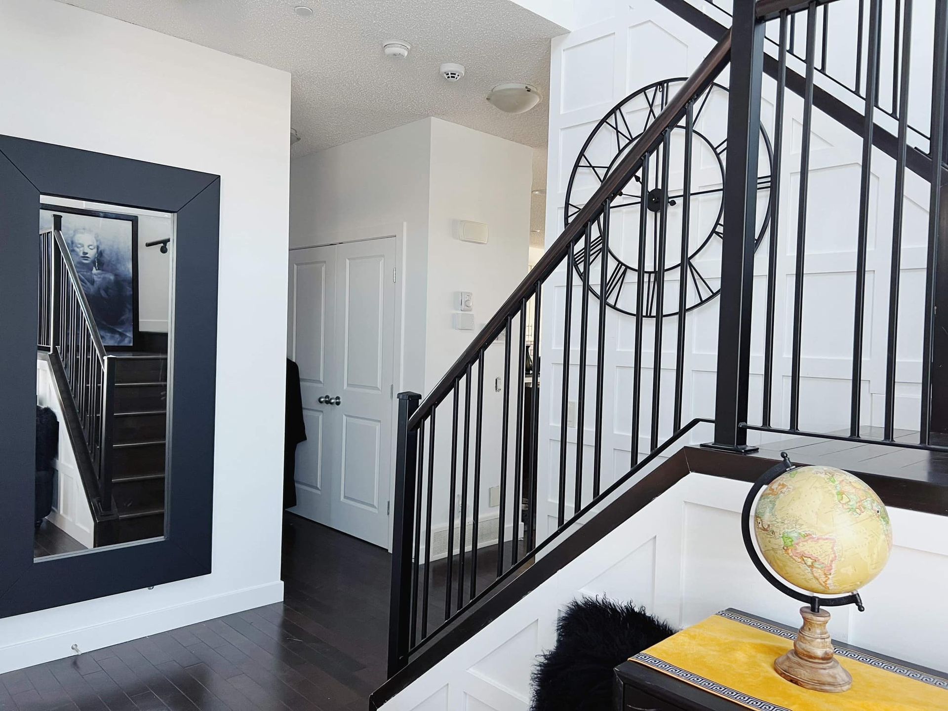 A staircase with a clock on the wall and a globe on a table