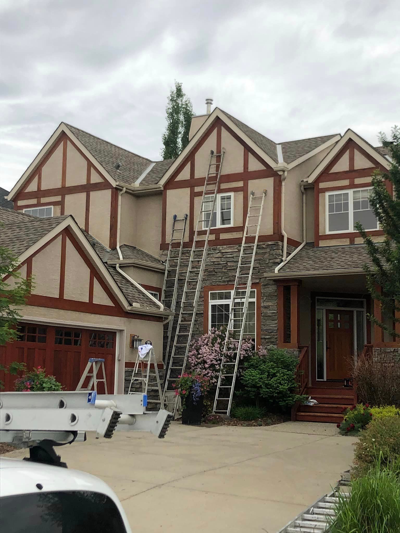 A man is standing on a ladder in front of a large house.