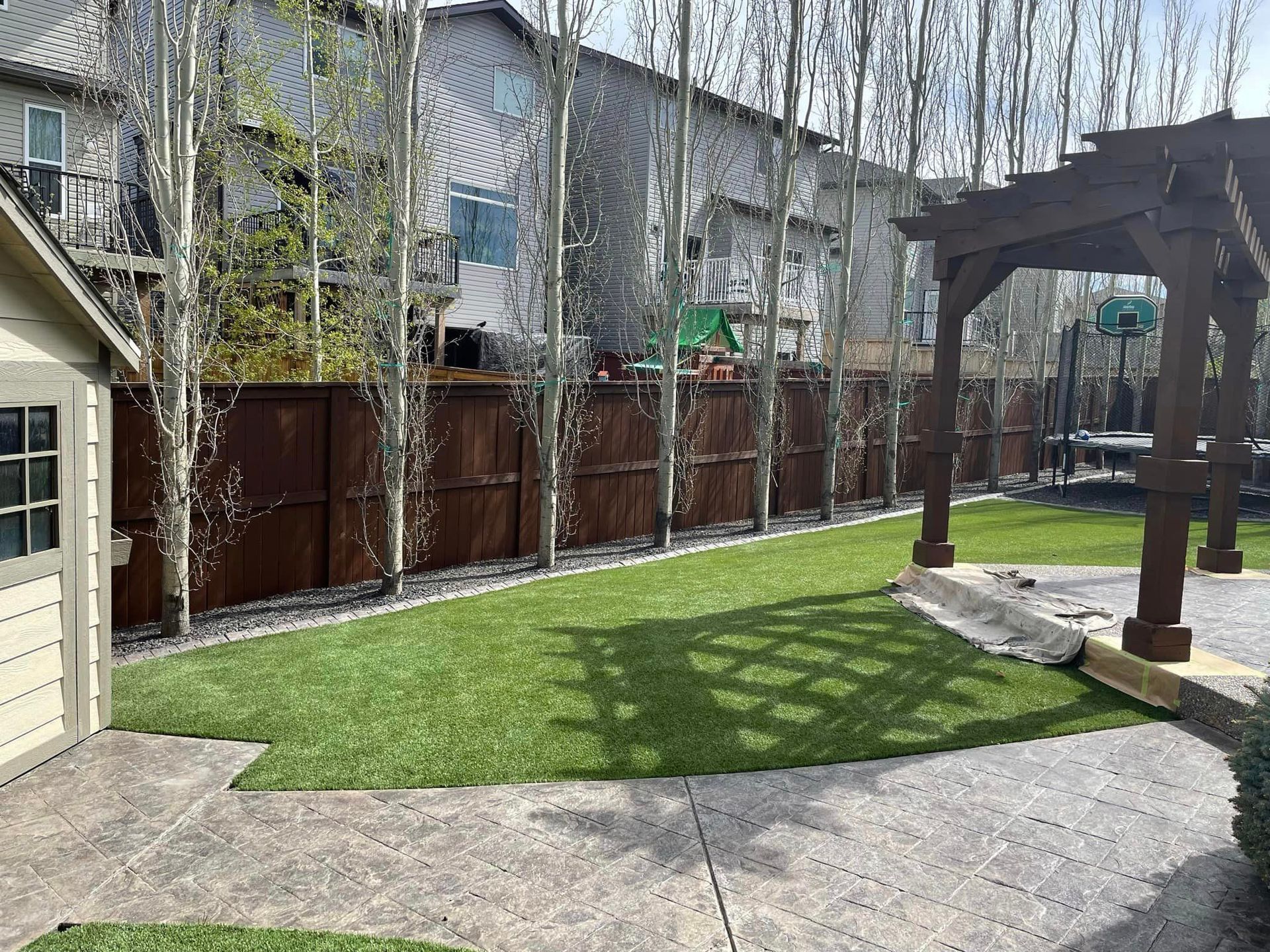 A backyard with a pergola and a basketball hoop.