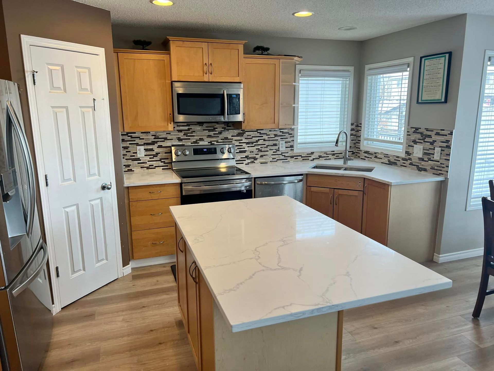 A kitchen with wooden cabinets , stainless steel appliances , and a large island.