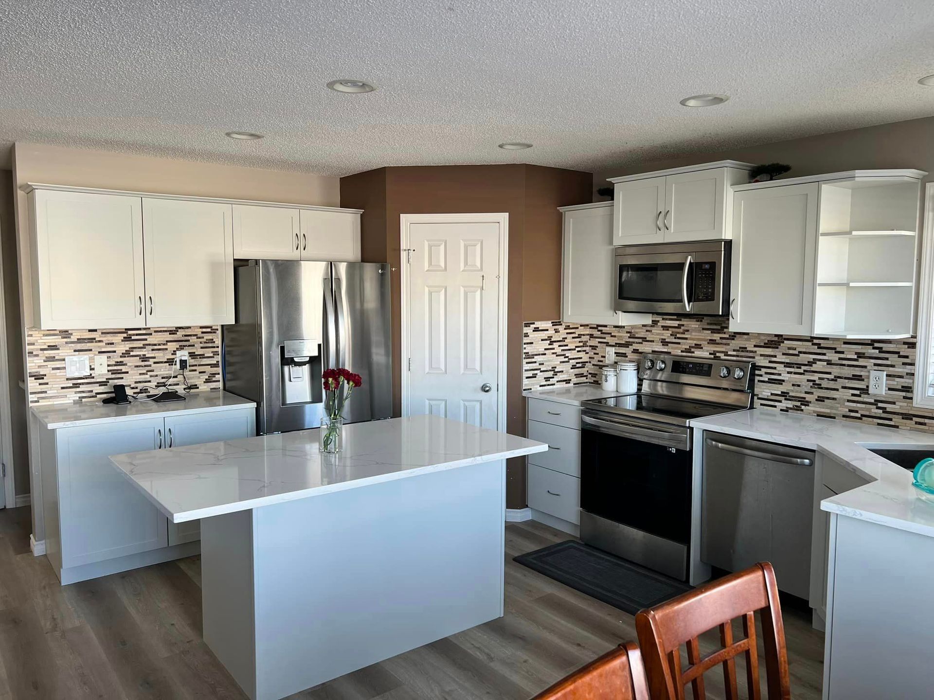 A kitchen with white cabinets , stainless steel appliances and a large island.