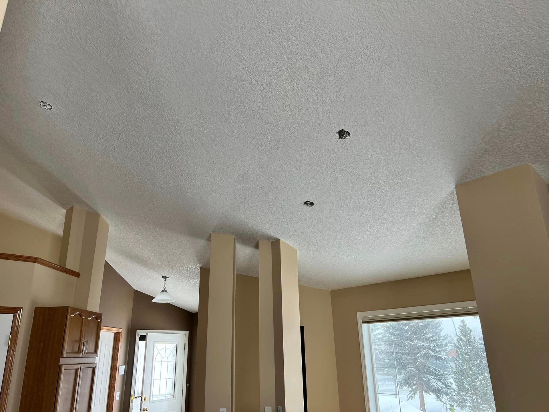 A living room with a white ceiling and a large window.