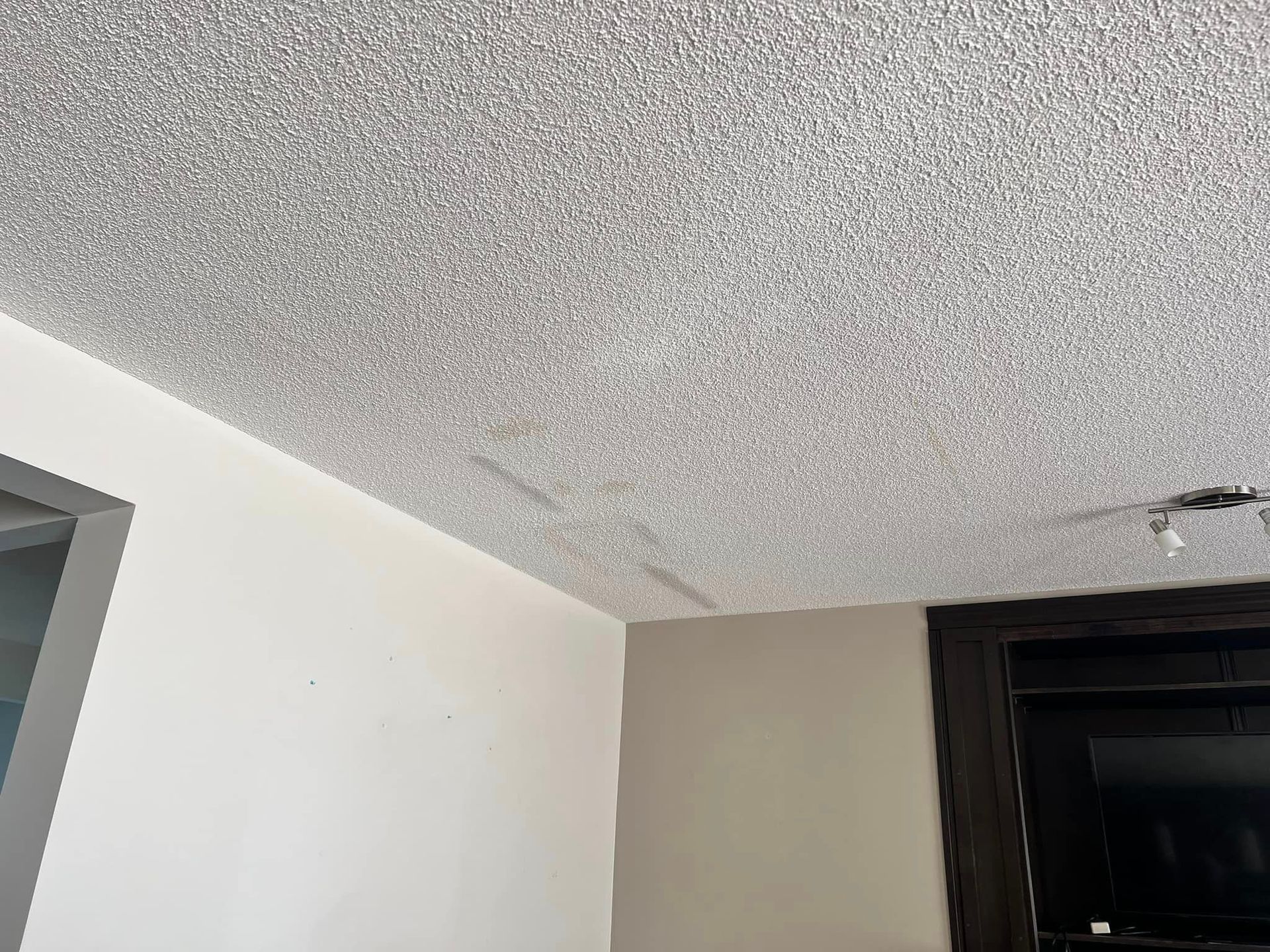 A living room with a gray ceiling and a flat screen tv.