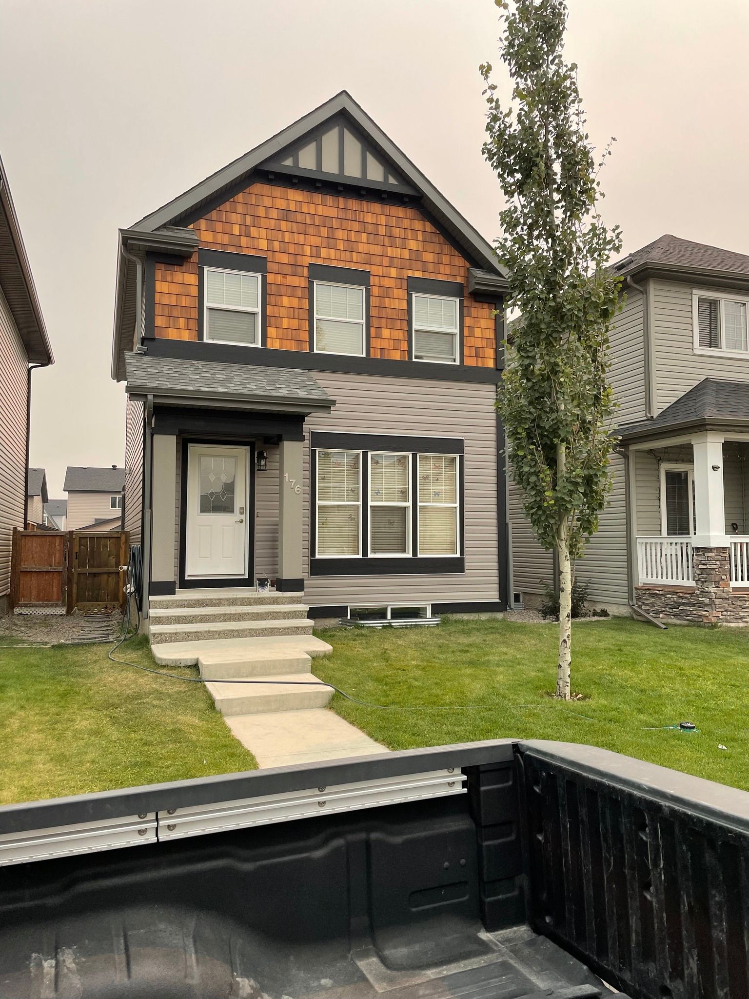The back of a truck is parked in front of a house.