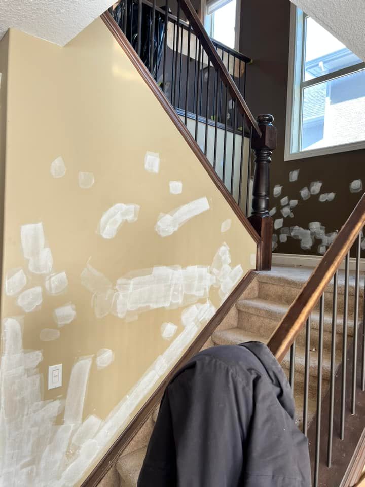 A person is sitting on a staircase with a jacket on the railing.