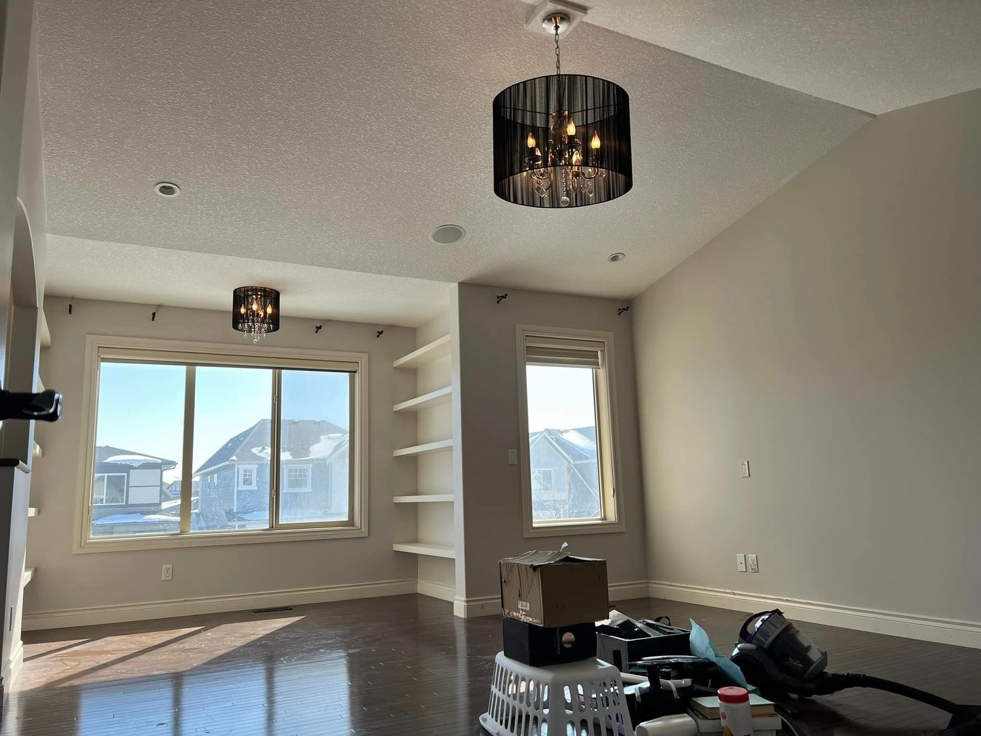 An empty living room with a chandelier hanging from the ceiling.