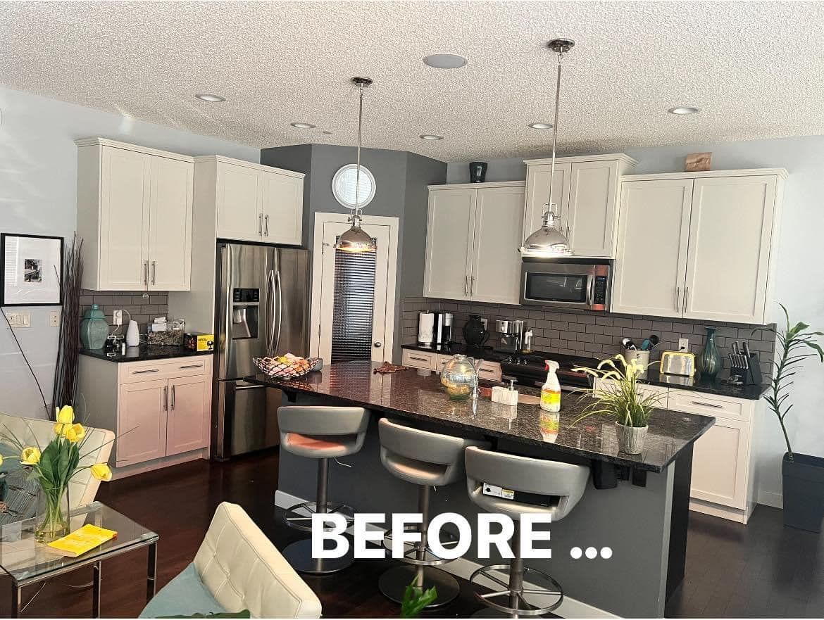 A before picture of a kitchen with white cabinets and black counter tops.
