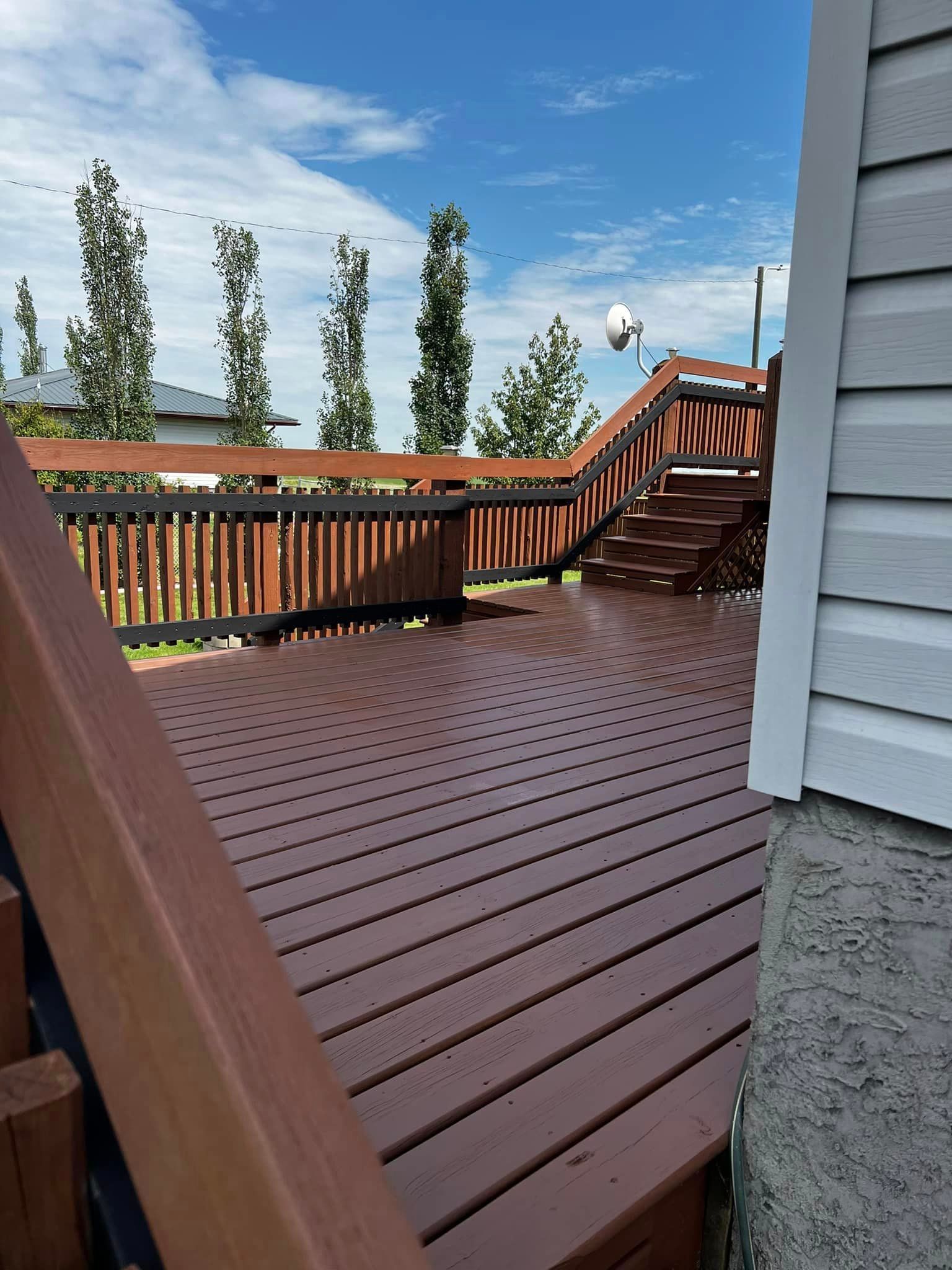 A wooden deck with stairs leading up to it next to a house.