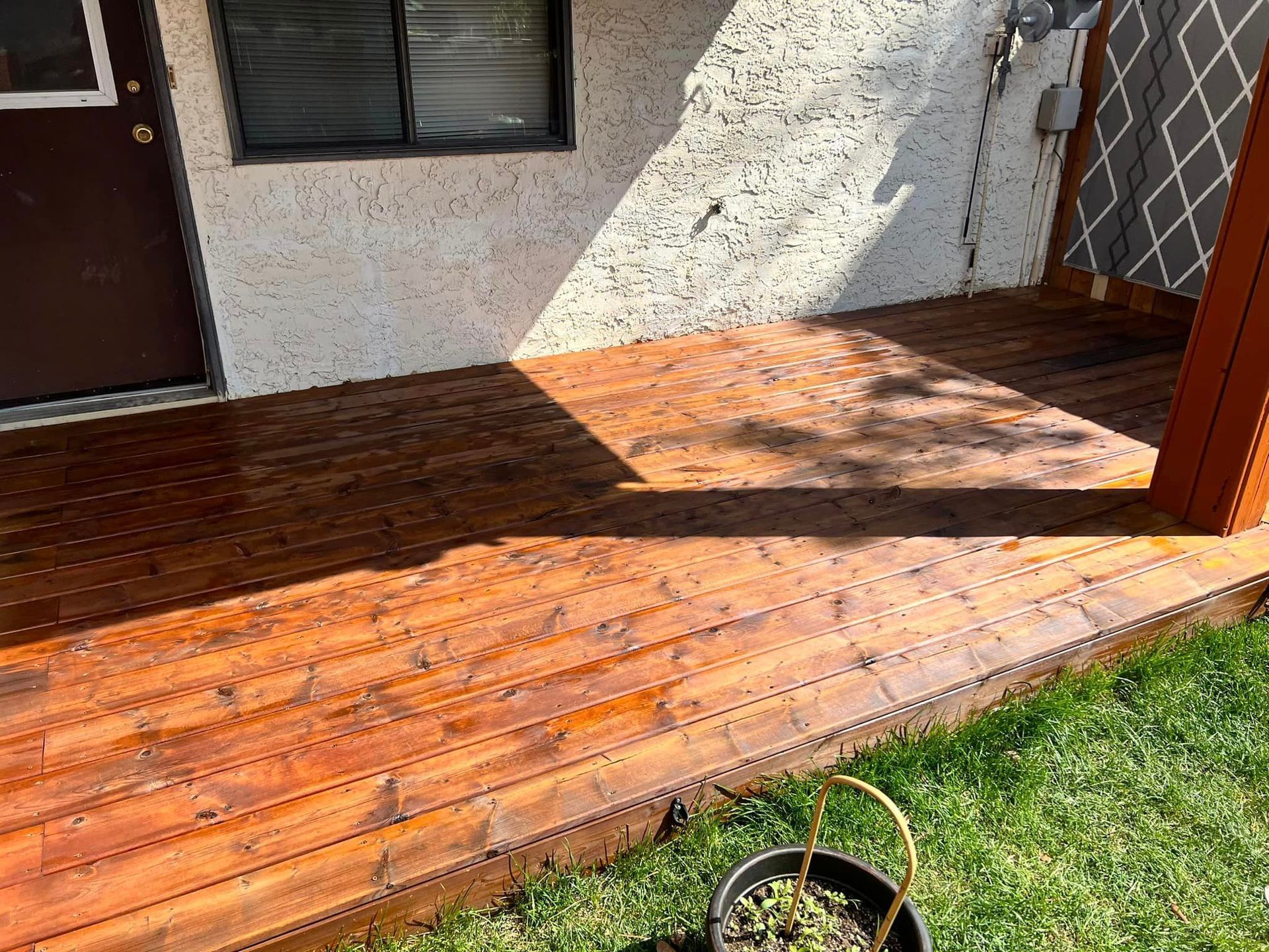 A wooden deck with a potted plant on it in front of a house.