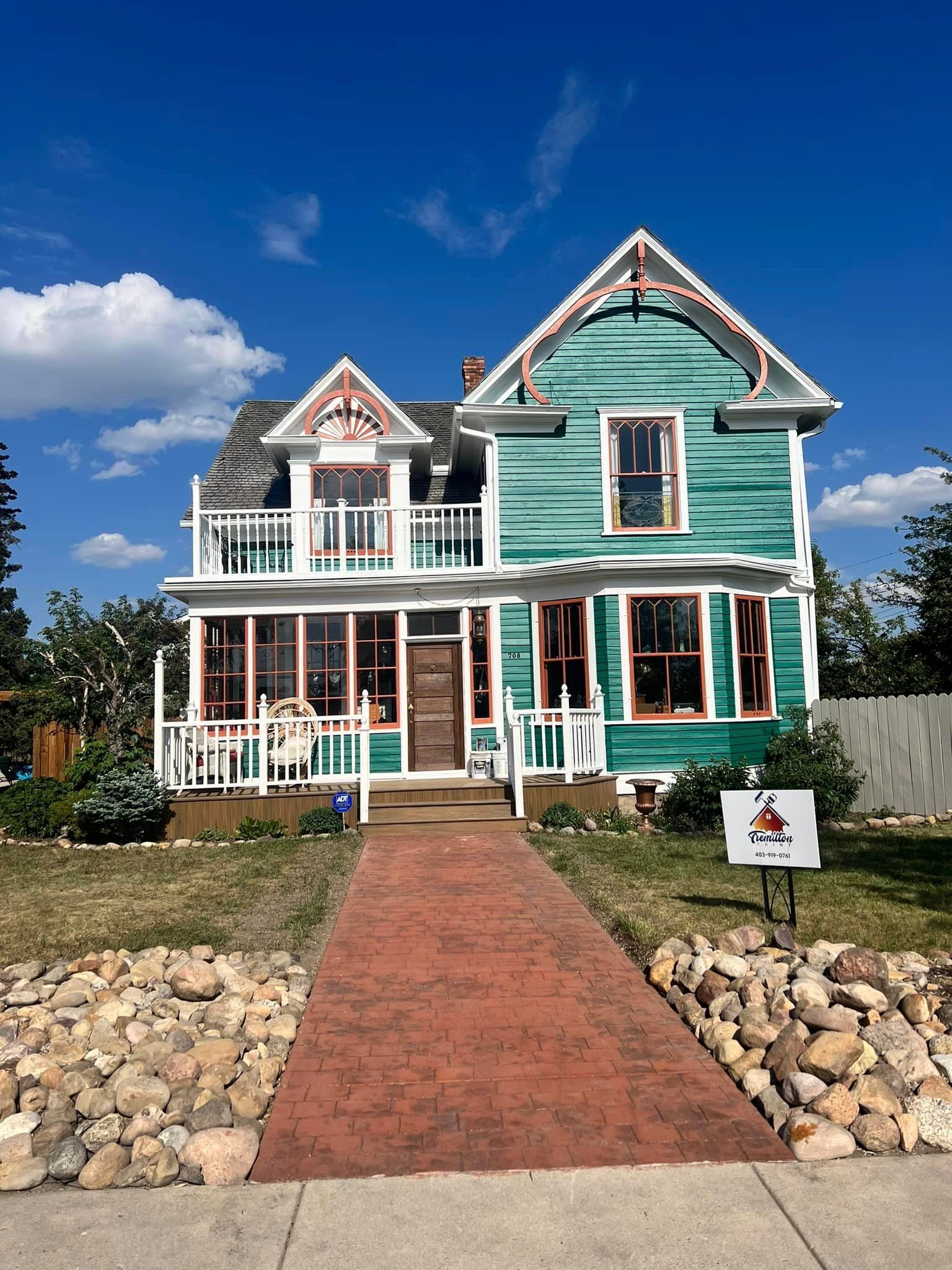 A large green house with a brick walkway leading to it