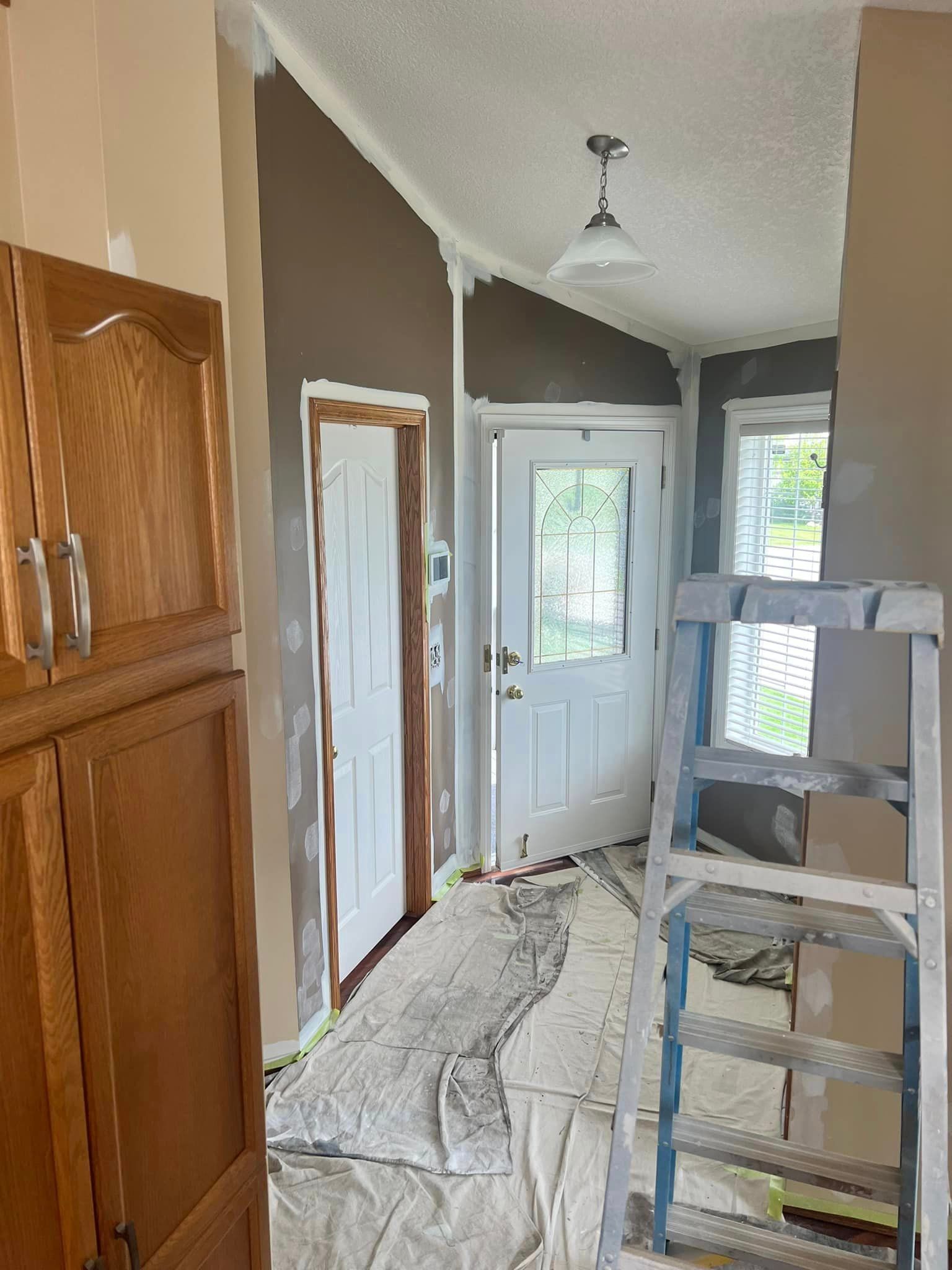 A room is being painted with a ladder in the foreground.