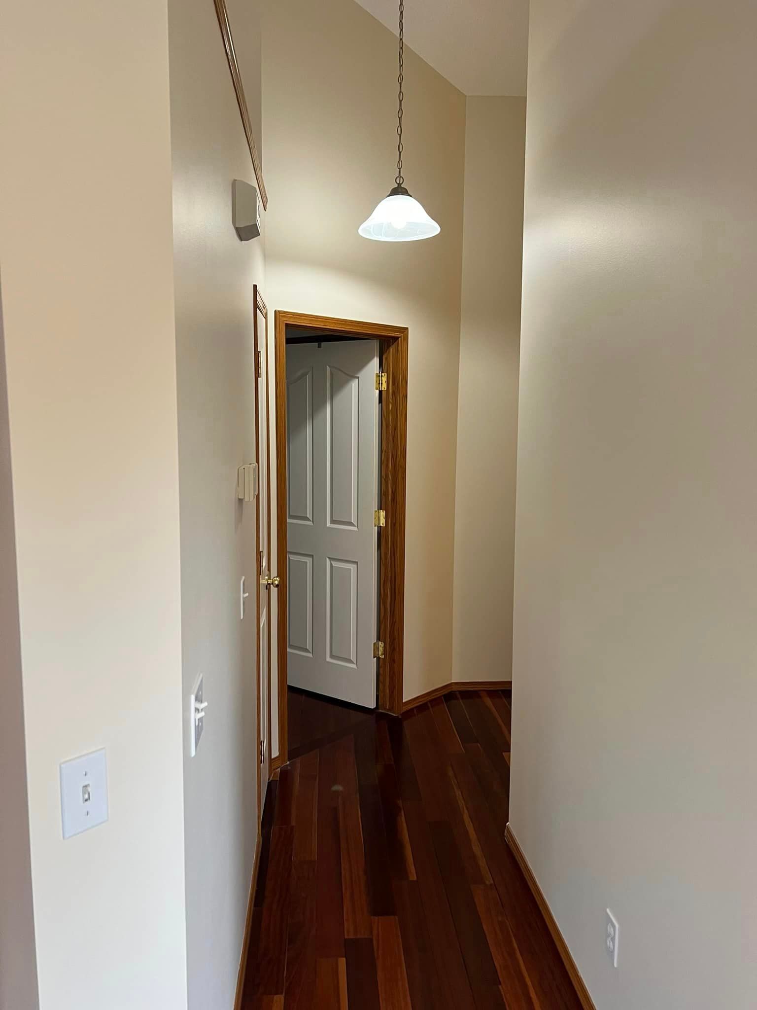 A hallway with hardwood floors and a light hanging from the ceiling