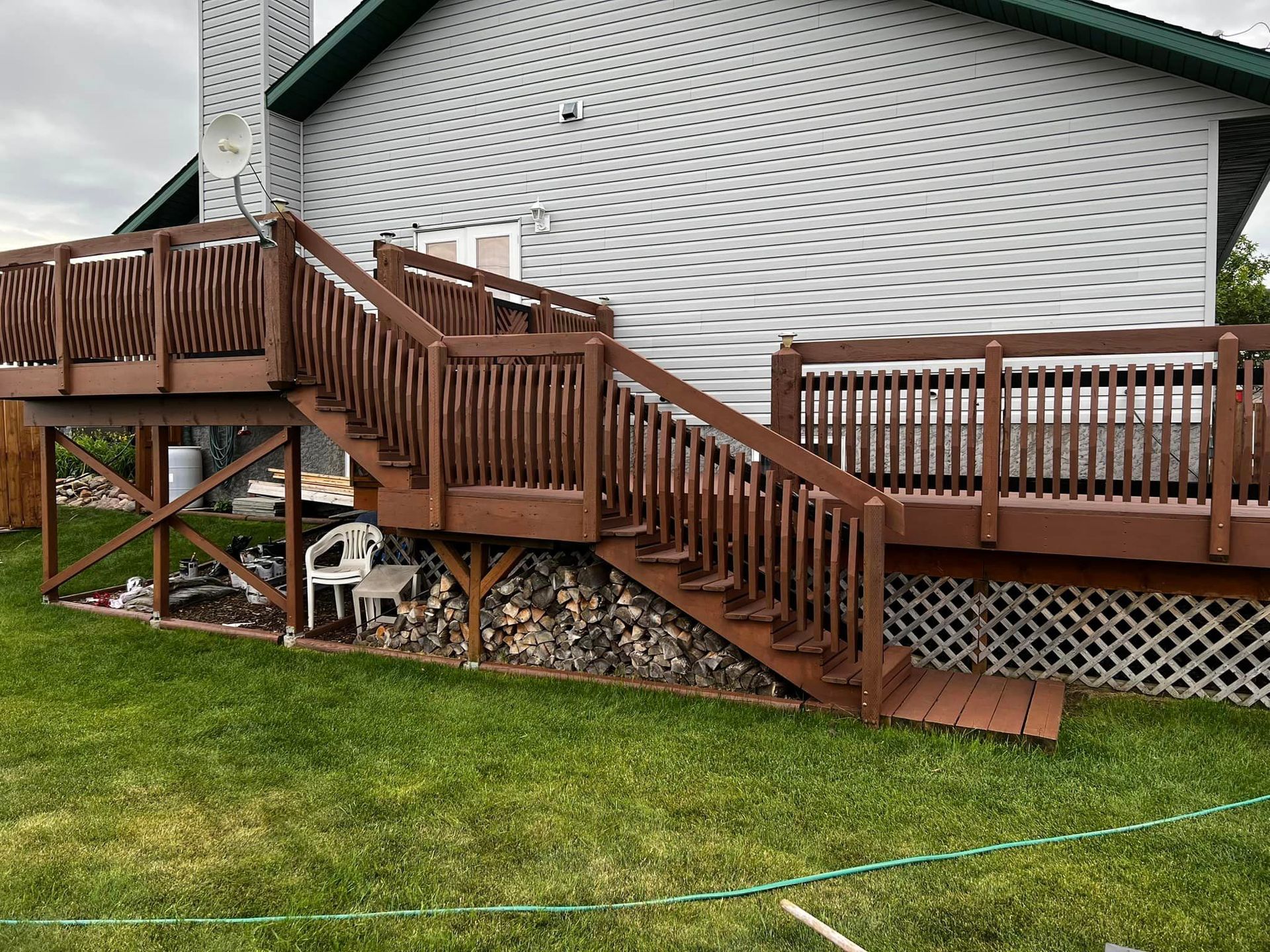 A wooden deck with stairs leading up to it is in front of a house.
