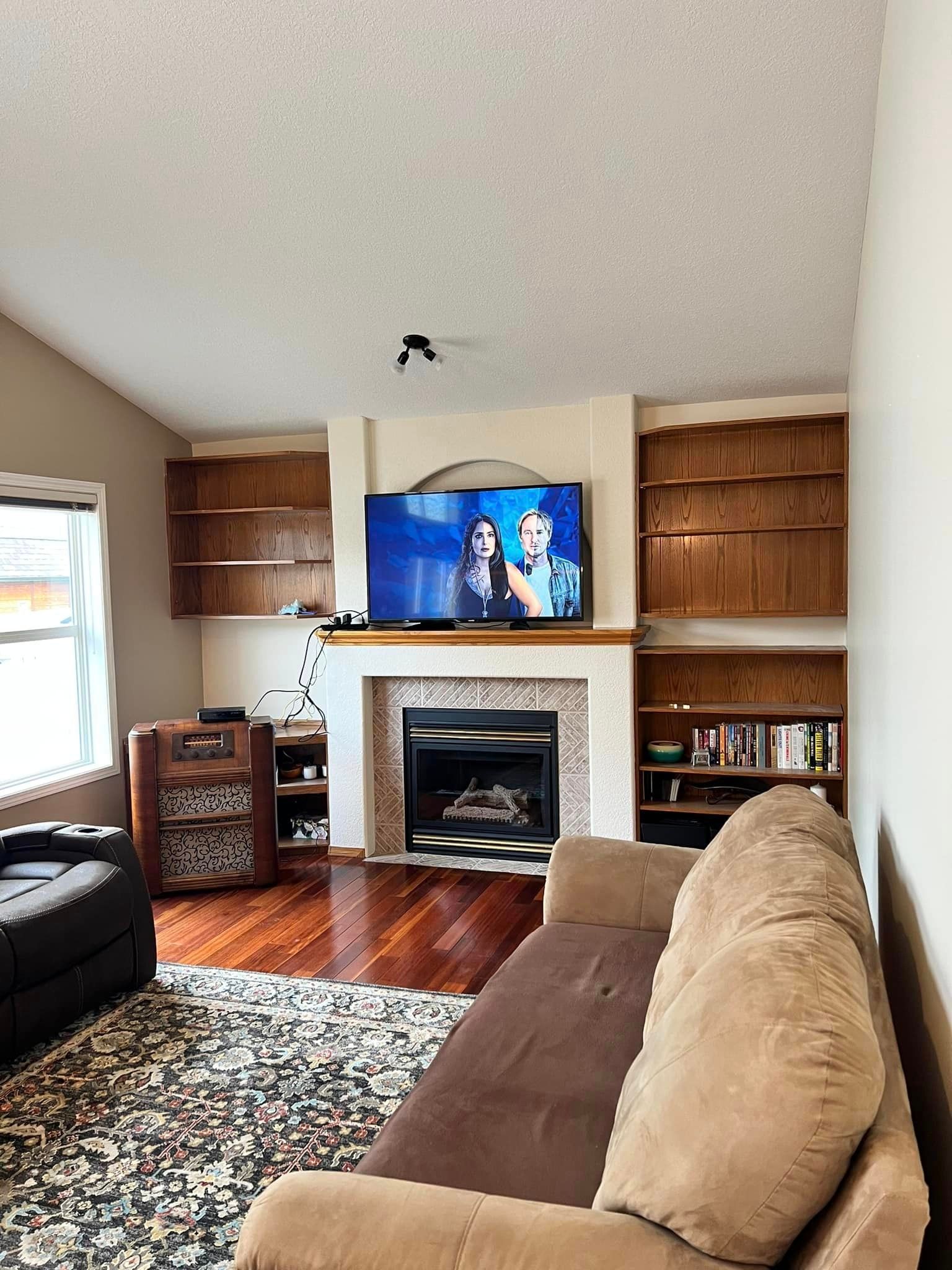 A living room with a couch , fireplace and television.