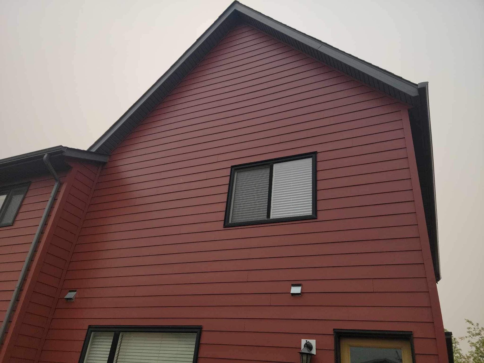 A red house with a black roof and a lot of windows