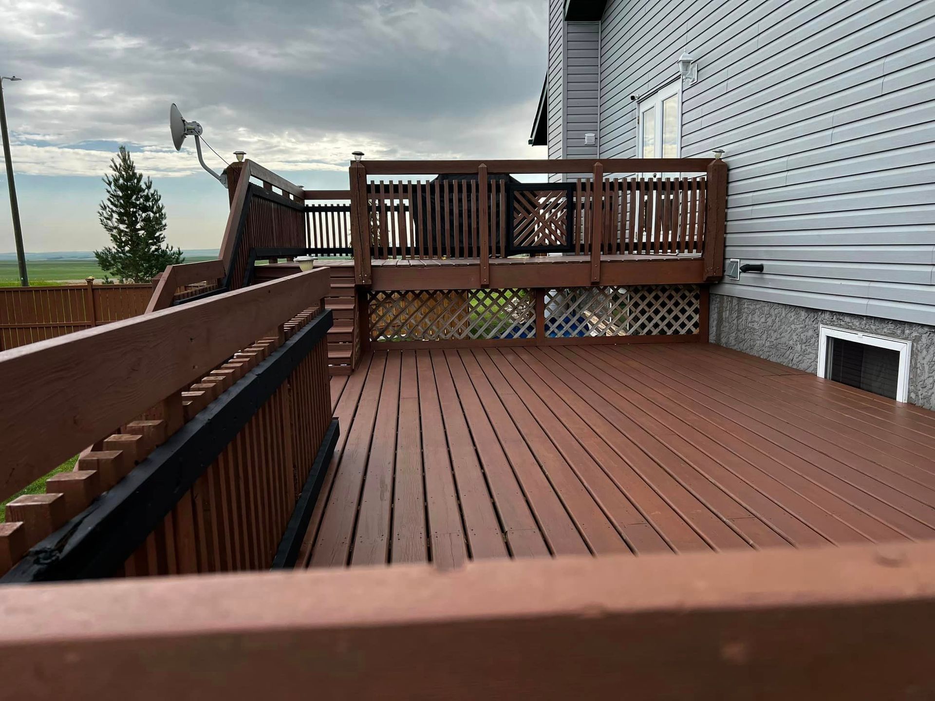 A large wooden deck is sitting in front of a house.
