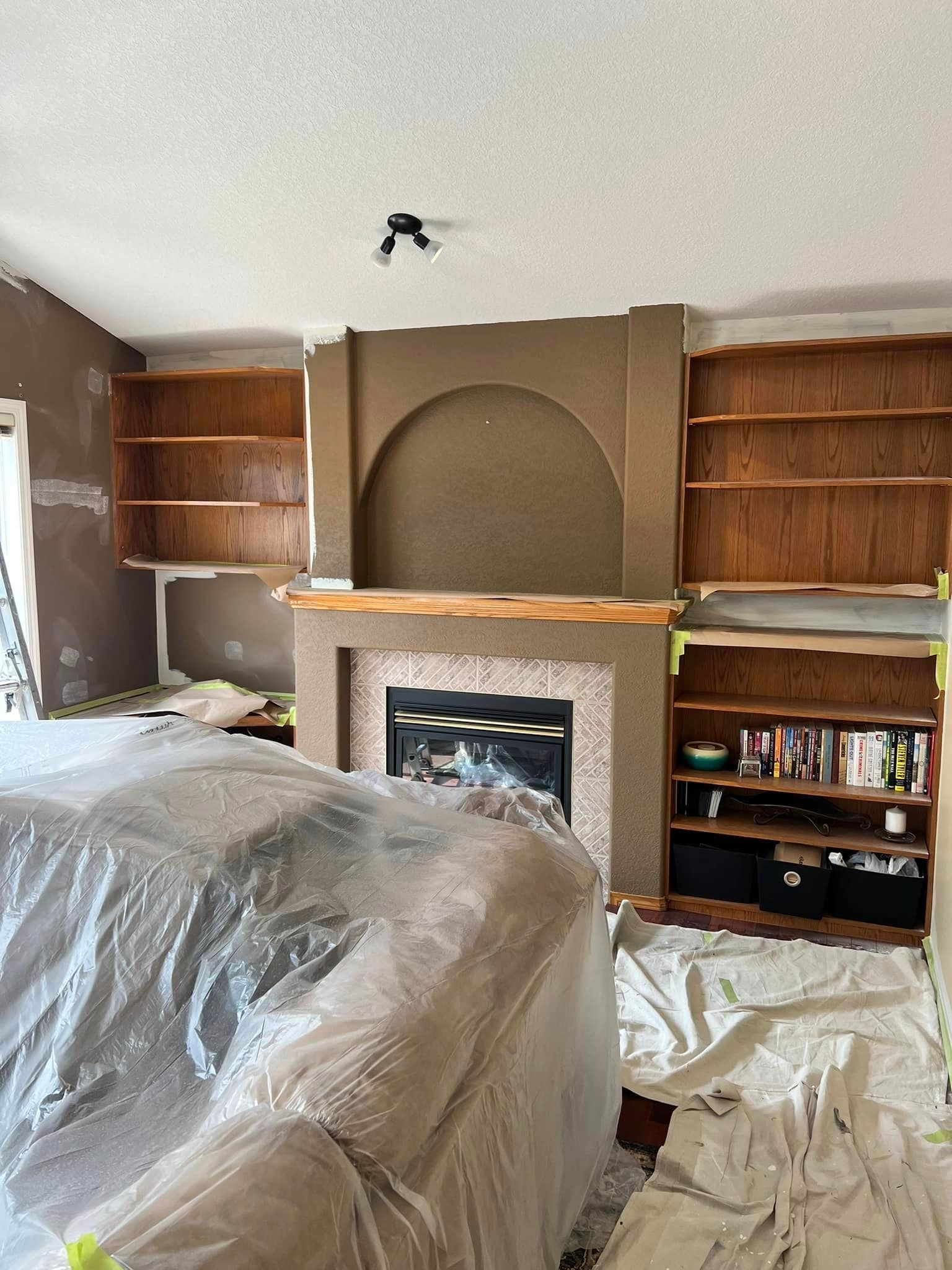 A living room with a fireplace and shelves being painted.