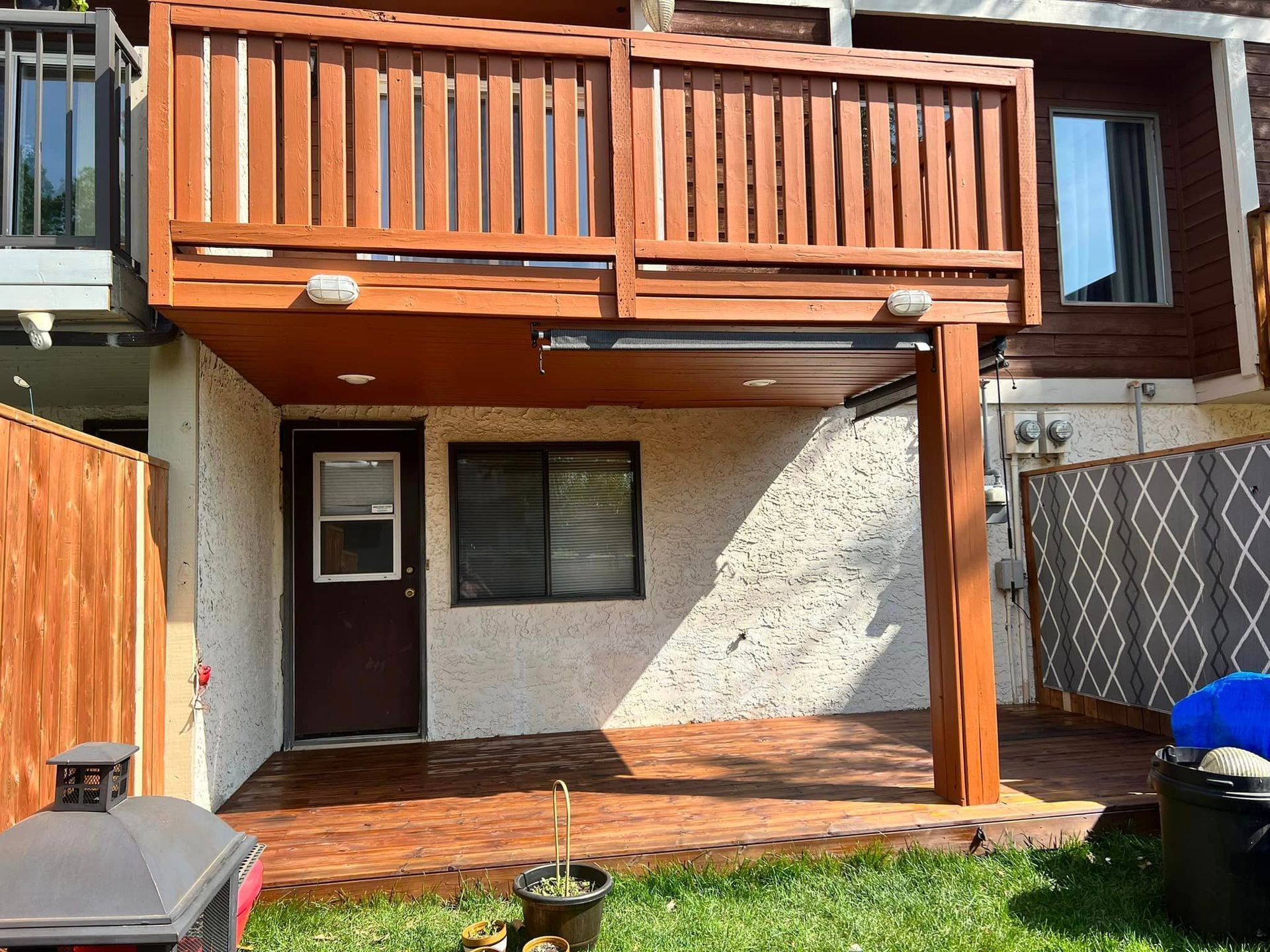 The backyard of a house with a wooden deck and a fence.